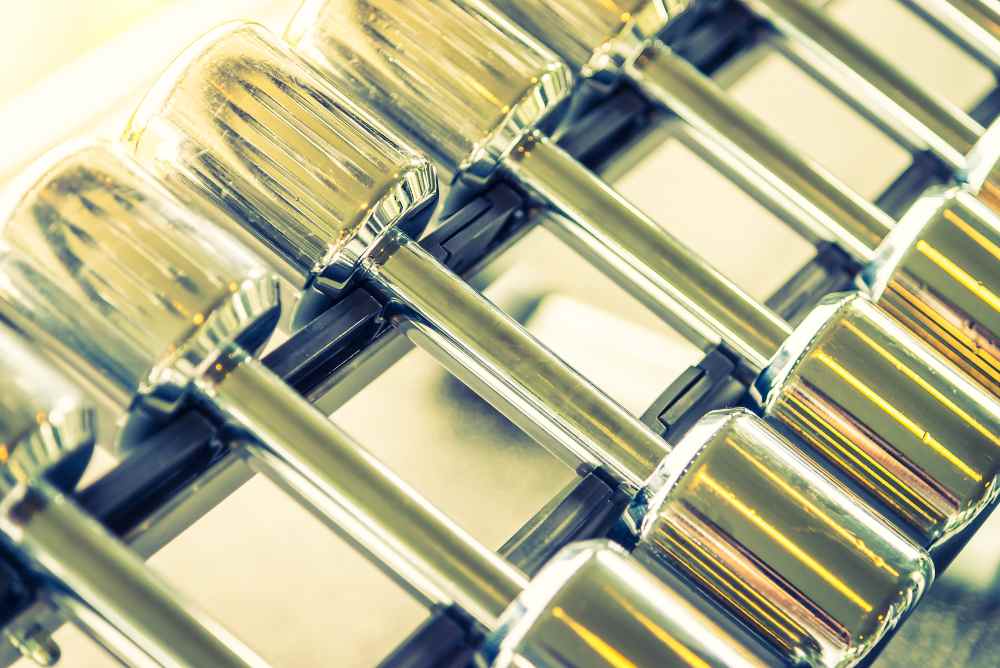 Row of shiny metal dumbbells arranged on a rack in a gym, their reflective surfaces reminiscent of the precision and quality found in copper injection molding for thermal and electrical parts.